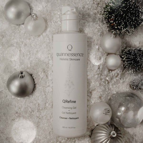 Quannessence QRefine Cleansing Gel bottle surrounded by decorative ornaments on a textured surface