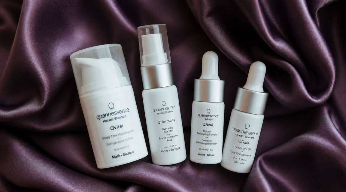 Set of Quannessence skincare products on a textured silky fabric background. Quannessence Skincare, professional skincare, Holistic Beauty, Made in Canada, Naturally Sourced, Active ingredients, women-owned, Face, toner, Serum, Oil, QBeauty Sleep, 4-piece kit, white branded cotton travel pouch