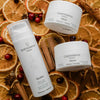 Quannessence Holistic Skincare BodyLuv products on a decorative background with oranges and cinnamon sticks