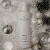 Quannessence QRefine Cleansing Gel bottle surrounded by decorative ornaments on a textured surface