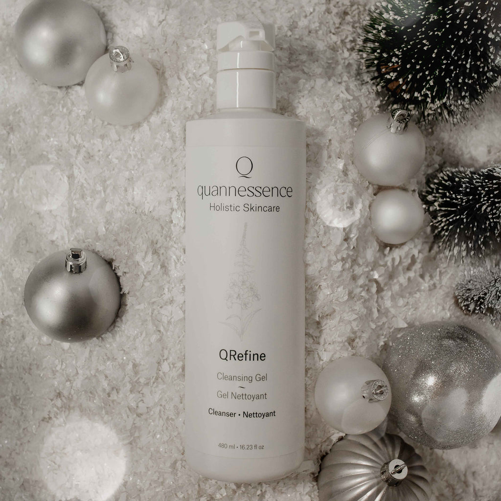 Quannessence QRefine Cleansing Gel bottle surrounded by decorative ornaments on a textured surface