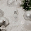 QGaia Skincare serum bottle with Christmas ornaments on a textured surface