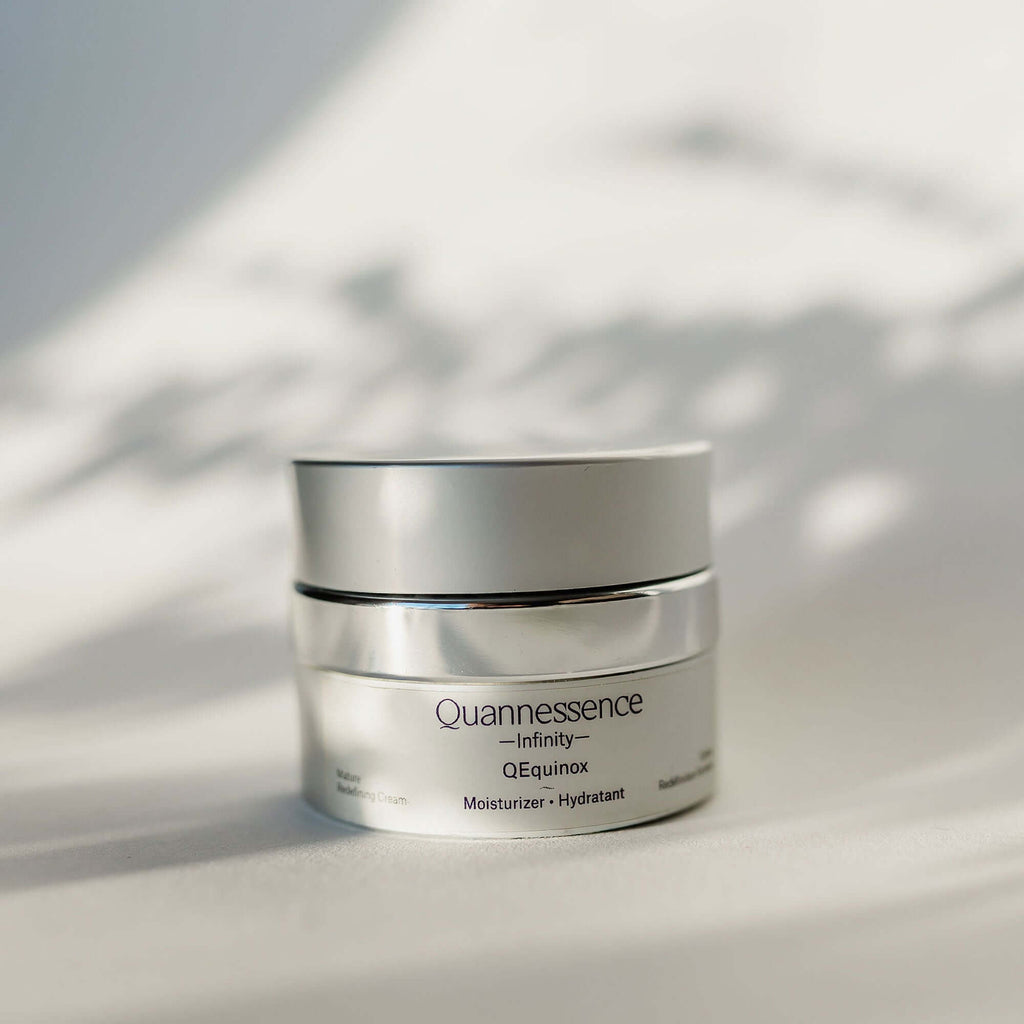 Skincare jar labeled 'Quannessence' on a light background. Quannessence Skincare, Infinity Collection, professional skincare, Holistic Beauty, Made in Canada, Naturally Sourced, Active ingredients, women-owned, Face, Moisturizer, Equinox, Equinox Age Renewal Cream, Silver packaging jar with silver lid