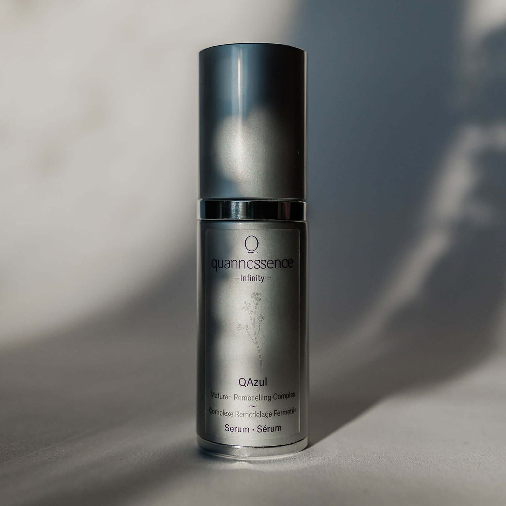 Skincare serum bottle labeled 'quannessence' on a neutral background. Quannessence Skincare, Infinity Collection, professional skincare, Holistic Beauty, Made in Canada, Naturally Sourced, Active ingredients, women-owned, Face, Serums, Qazul, Azul Rejuvenating Serum, Silver packaging with silver lid and pump