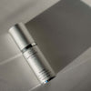 Skincare serum bottle labeled 'quantessence' on a neutral background. Quannessence Skincare, Infinity Collection, professional skincare, Holistic Beauty, Made in Canada, Naturally Sourced, Active ingredients, women-owned, Face, Serum, QSolstice, Solstice Redefining Serum, Silver packaging with silver lid and pump