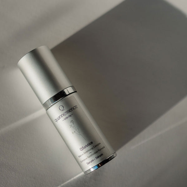 Skincare serum bottle labeled 'quantessence' on a neutral background. Quannessence Skincare, Infinity Collection, professional skincare, Holistic Beauty, Made in Canada, Naturally Sourced, Active ingredients, women-owned, Face, Serum, QSolstice, Solstice Redefining Serum, Silver packaging with silver lid and pump