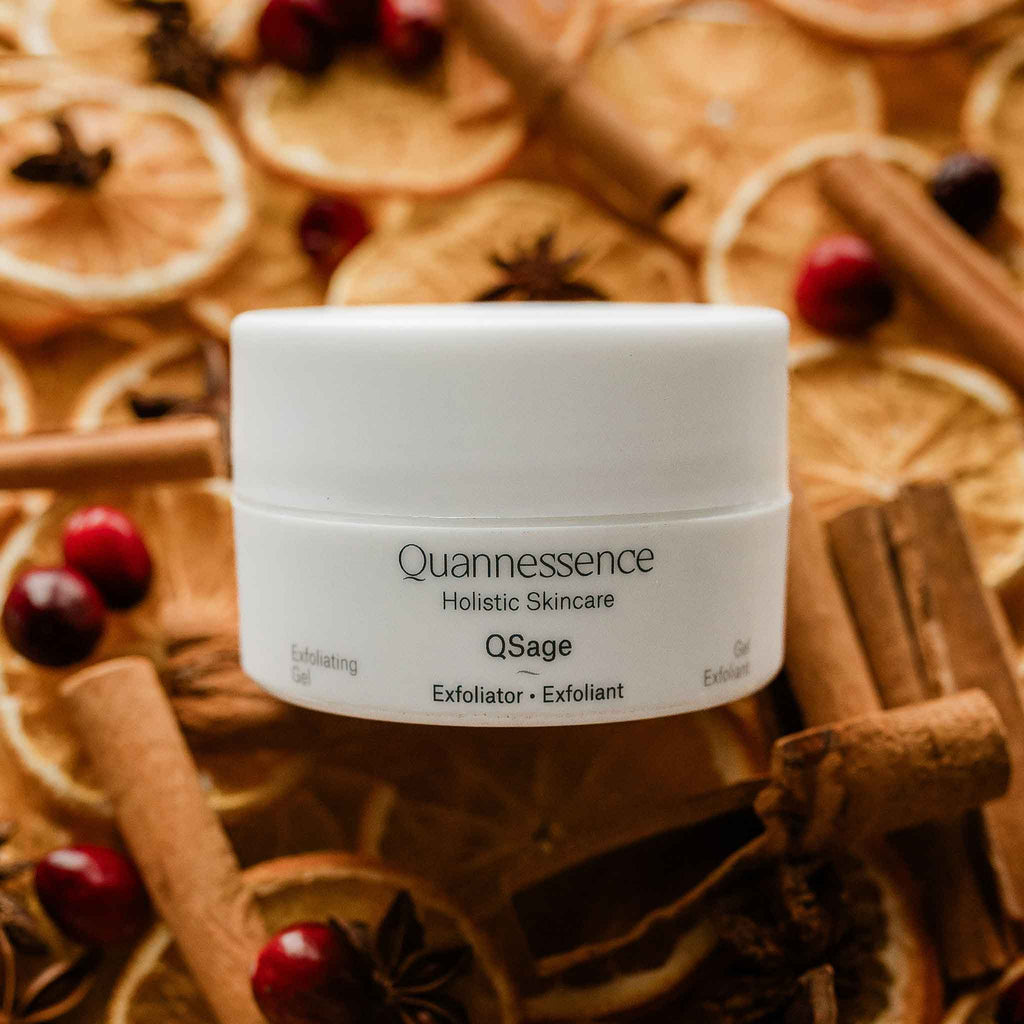 Quannessence Holistic Skincare  jar with cinnamon sticks and oranges in the background
