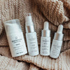Set of Quannessence skincare products on a textured fabric background. Quannessence Skincare, professional skincare, Holistic Beauty, Made in Canada, Naturally Sourced, Active ingredients, women-owned, Face, toner, Serum, Oil, QBeauty Sleep, 4-piece kit, white branded cotton travel pouch