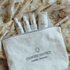 Set of Quannessence skincare products on a floral-patterned fabric background. Quannessence Skincare, professional skincare, Holistic Beauty, Made in Canada, Naturally Sourced, Active ingredients, women-owned, Face, toner, Serum, Oil, QBeauty Sleep, 4-piece kit, white branded cotton travel pouch background