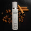 Quannessence Holistic Skincare bottle labeled 'quannessence' with cinnamon sticks and star anise on a dark background