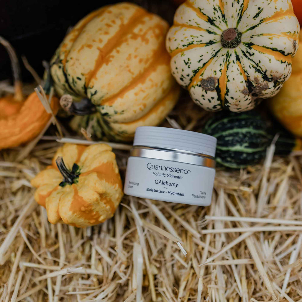 Quannessence skincare product with pumpkins on straw. Quannessence Skincare, professional skincare, Holistic Beauty, Made in Canada, Naturally Sourced, Active ingredients, women-owned, Face, Moisturizer, Lotion, Cream, QAlchemy, Alchemist Revitalizing Cream, white jar