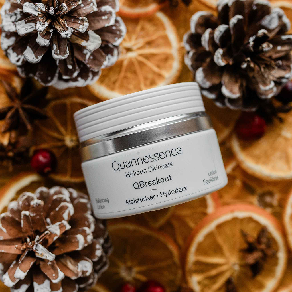 Quannessence skincare jar on a decorative background with pine cones and oranges