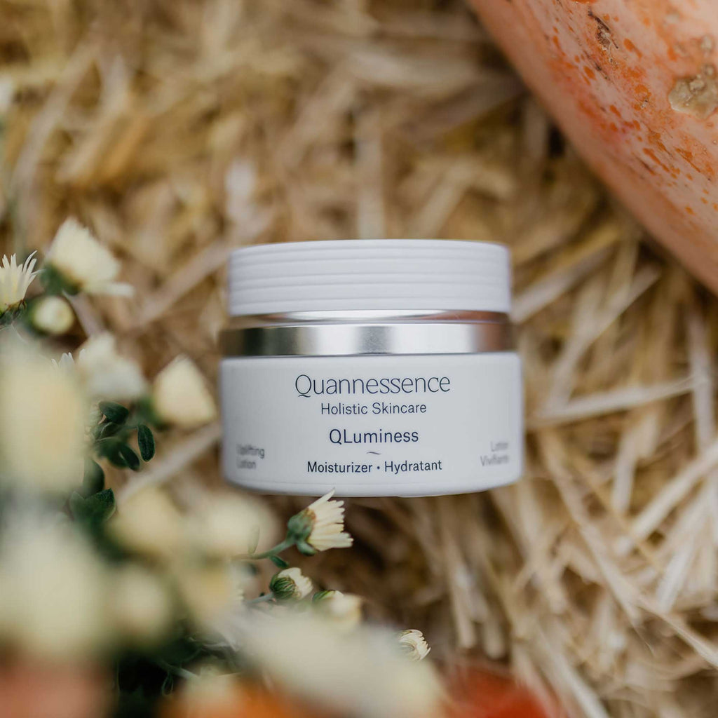 Quannessence skincare jar on a rustic background with flowers and a pumpkin. Quannessence Skincare, professional skincare, Holistic Beauty, Made in Canada, Naturally Sourced, Active ingredients, women-owned, Face, Moisturizer, Lotion, Cream, QLuminess, Luminess Face Lotion, white jar