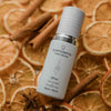 Quannessence Holistic Skincare serum bottle labelled 'quannessence' on a decorative background with dried oranges and cinnamon sticks.
