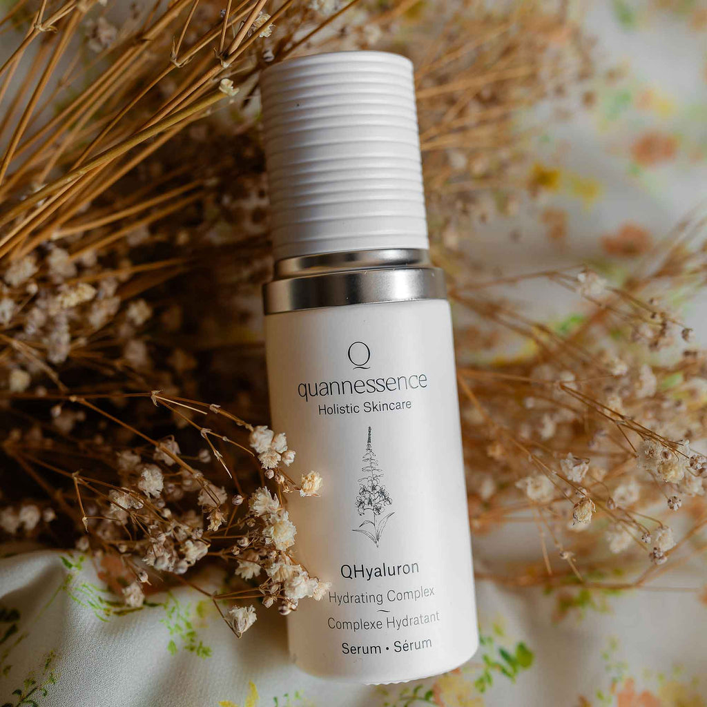 QHyaluron Hydrating Complex by Quannessence, Skincare serum bottle with 'quannessence' branding on a floral background. Quannessence Skincare, professional skincare, Holistic Beauty, Made in Canada, Naturally Sourced, Active ingredients, women-owned, Face, Serum, QHYaluron, Hyaluronic (PUR) Hydrating Serum, white glass packaging with white lid & pump