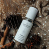 Skincare serum bottle labeled 'quannessence' on a textured fabric background with dried herbs and spices. Quannessence Skincare, professional skincare, Holistic Beauty, Made in Canada, Naturally Sourced, Active ingredients, women-owned, Face, Serum, QHYaluron, Hyaluronic (PUR) Hydrating Serum, white glass packaging with white lid & pump