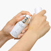 Person holding a skincare bottle and applying product to their hand against a white background. Quannessence Skincare, professional skincare, Holistic Beauty, Made in Canada, Naturally Sourced, Active ingredients, women-owned, Face, Serum, QPearl, Pearlessence Brightening Gel, white glass packaging with white lid & pump
