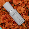 Skincare serum bottle labeled 'quannessence' on a bed of orange flowers. Quannessence Skincare, professional skincare, Holistic Beauty, Made in Canada, Naturally Sourced, Active ingredients, women-owned, Face, Serum, QPearl, Pearlessence Brightening Gel, white glass packaging with white lid & pump