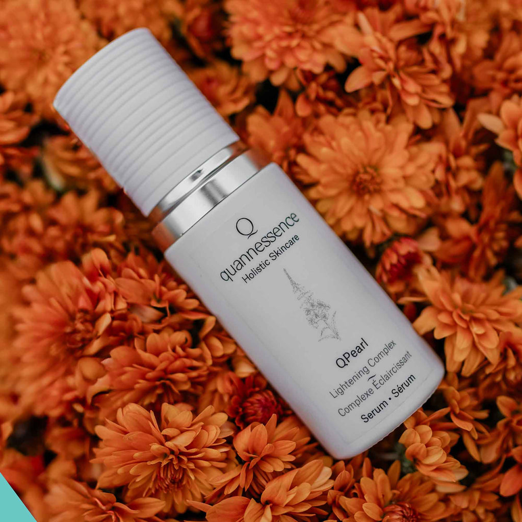Skincare serum bottle labeled 'quannessence' on a bed of orange flowers. Quannessence Skincare, professional skincare, Holistic Beauty, Made in Canada, Naturally Sourced, Active ingredients, women-owned, Face, Serum, QPearl, Pearlessence Brightening Gel, white glass packaging with white lid & pump