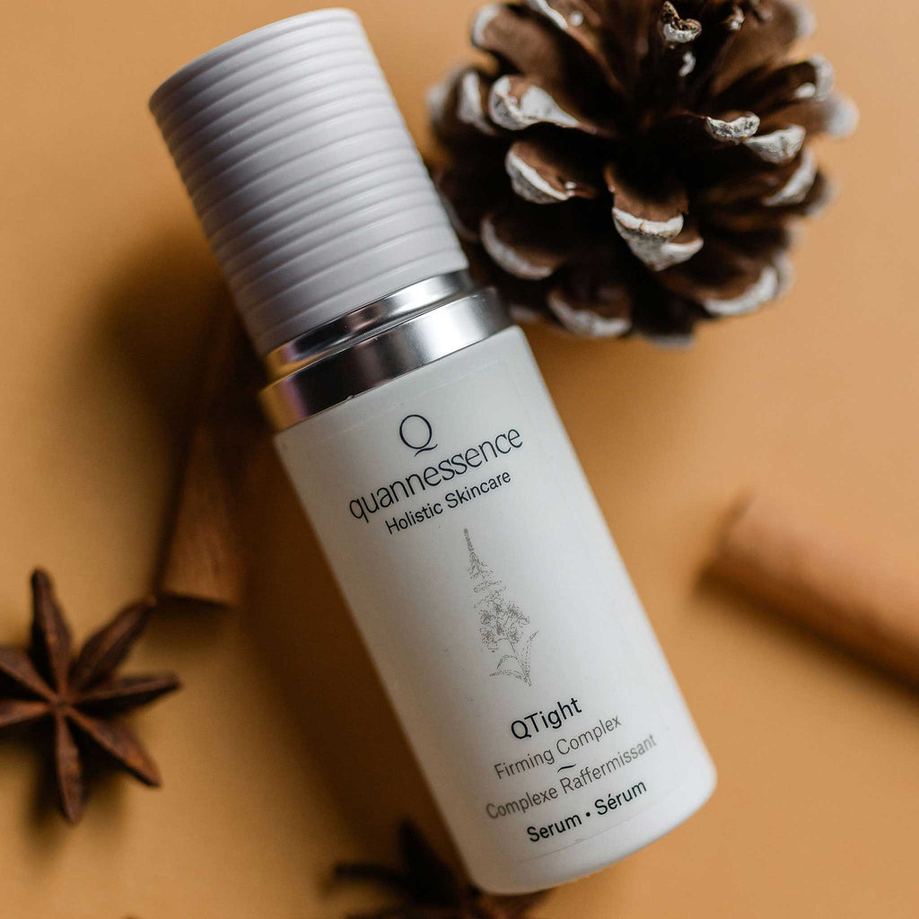 Quannessence Holistic Skincare serum bottle with decorative elements on a brown background