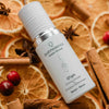 Quannessence Holistic Skincare serum bottle labeled 'quannessence' on a decorative background with oranges and cinnamon sticks.
